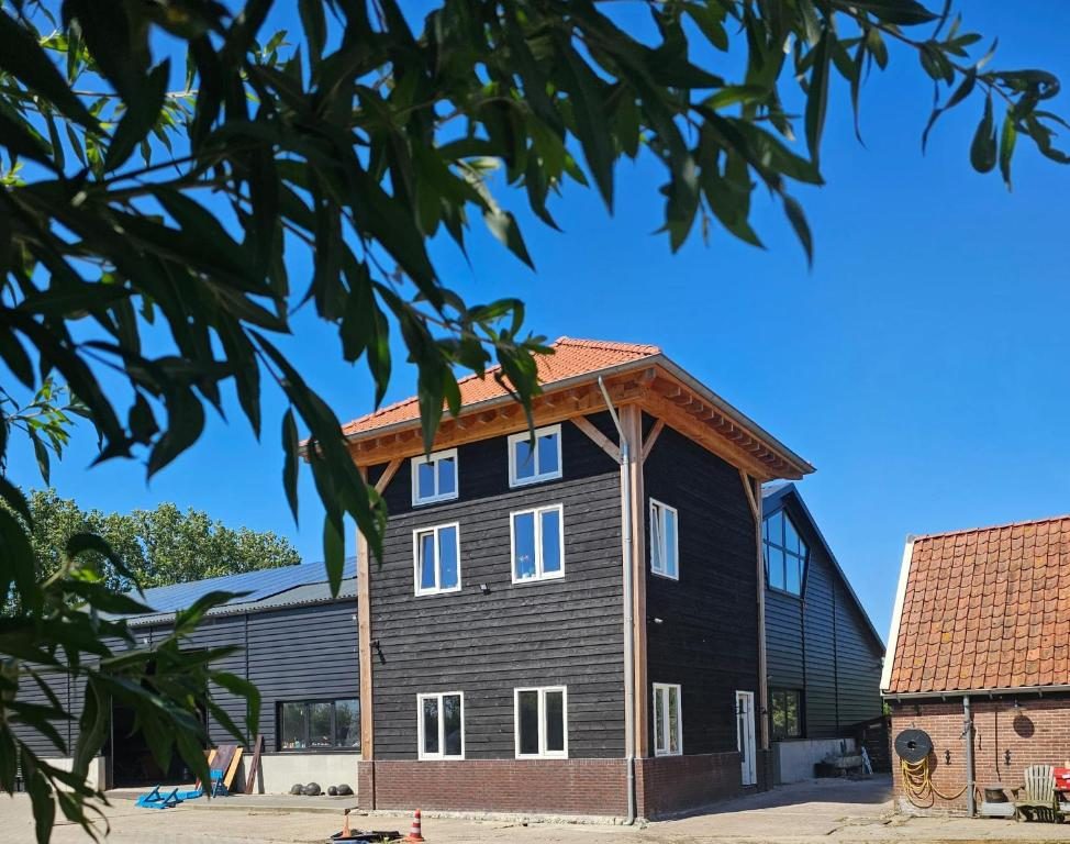 De Gouwe Hooiberg in Hoogwoud, een zwart houten bijgebouw met rode pannen naast de stolpboerderij