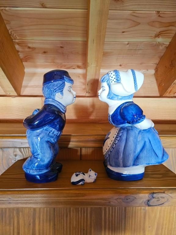 Twee Delfts blauwe beeldjes van een Hollands paar op een houten plank
