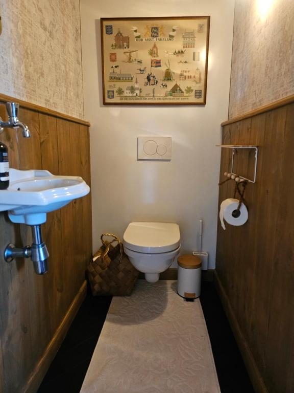 Apart toilet met houten lambrisering en een West-Fries borduurwerk aan de wand